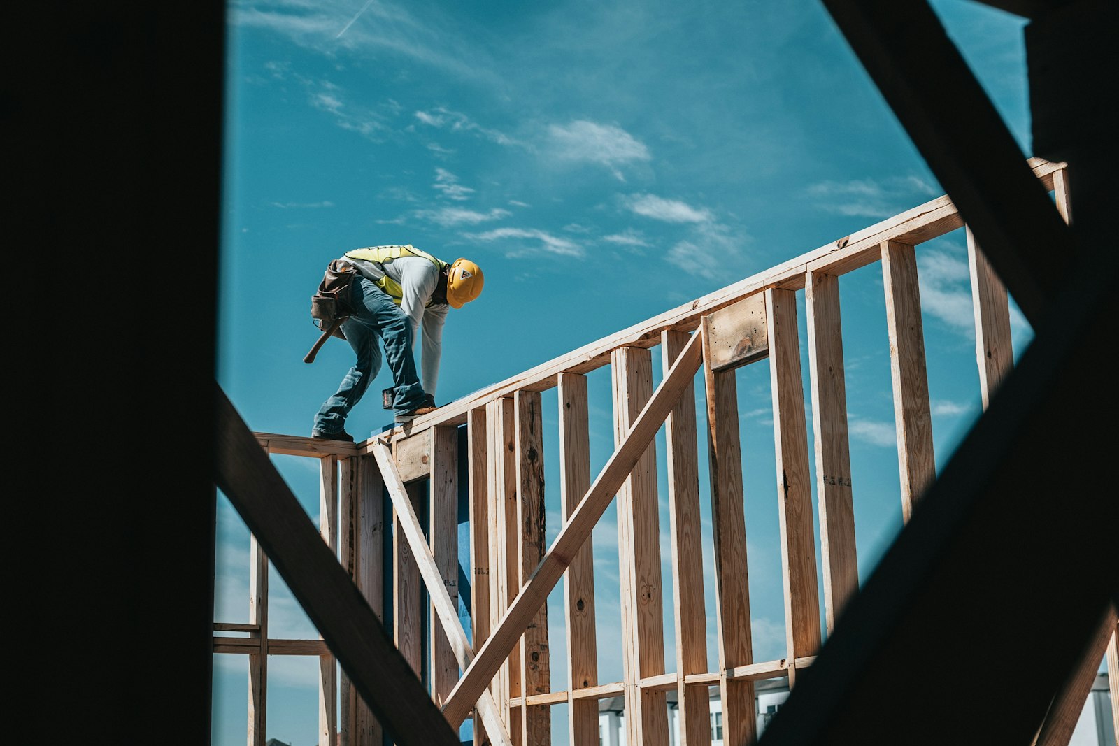 A framer working on a roof against a blue sky
