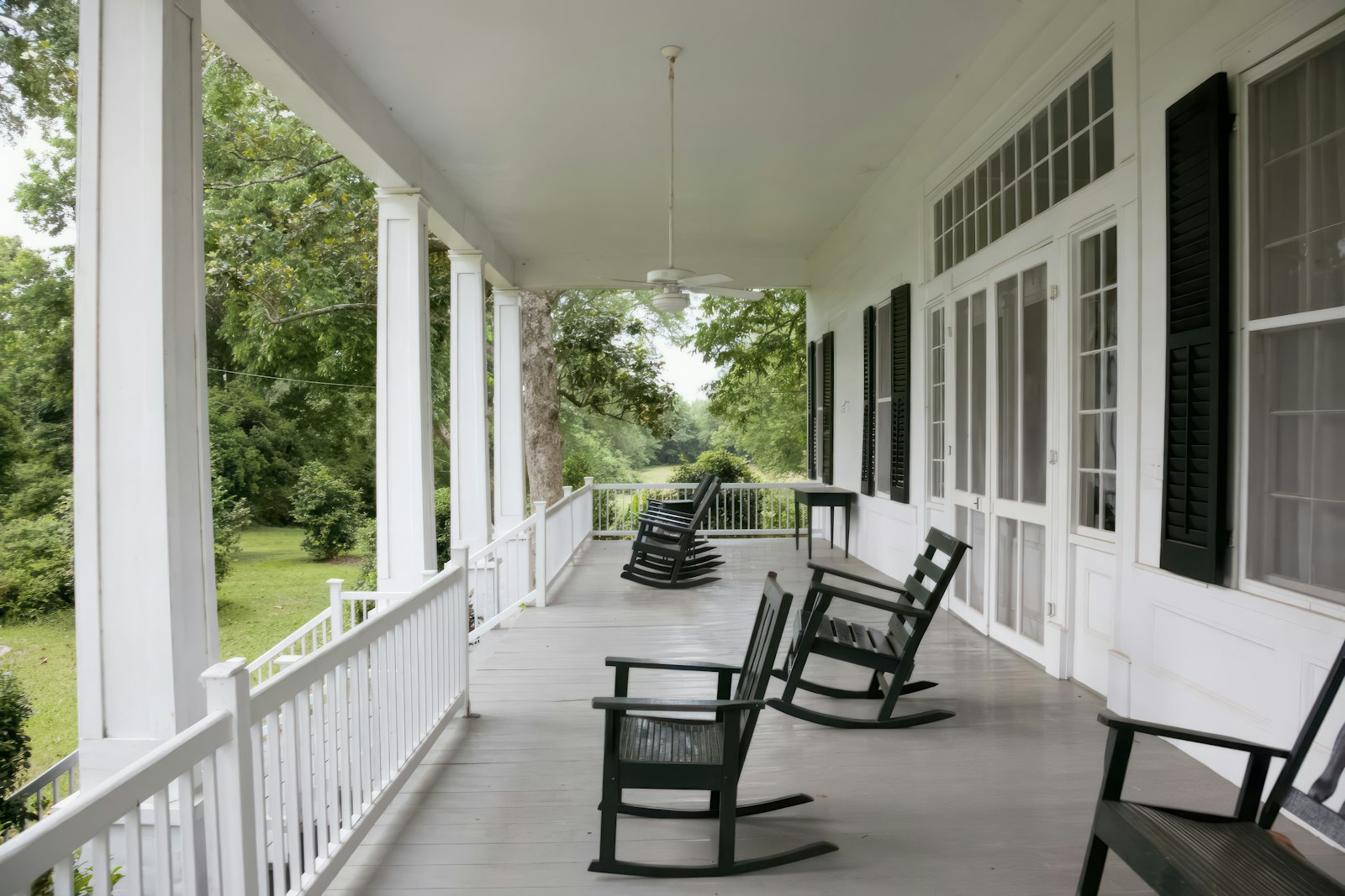 A white porch with rocking chairs on a historic inn