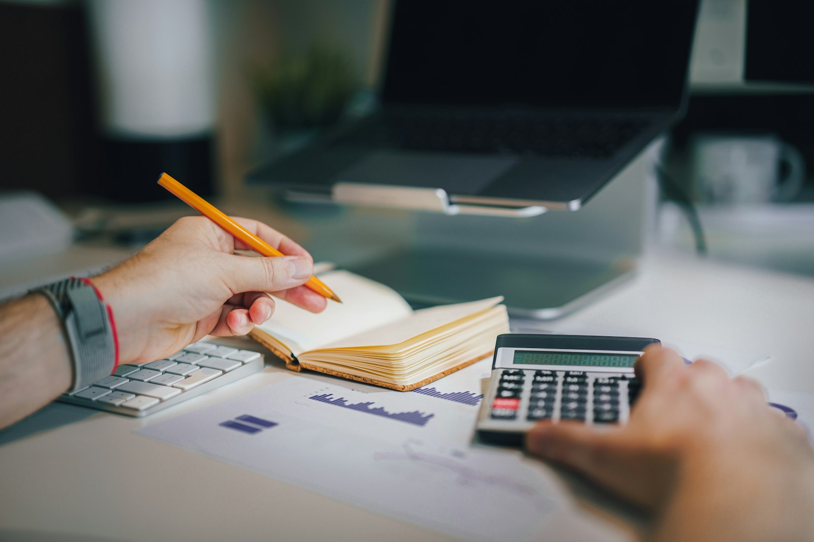 A desk with a calculator, a notebook, and a pen